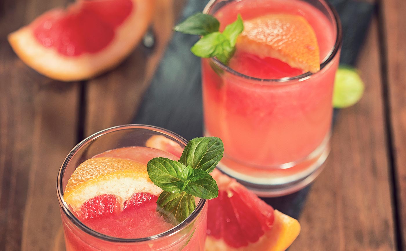 Refreshing grapefruit cocktails garnished with mint leaves on a wooden table | MSC Cruises