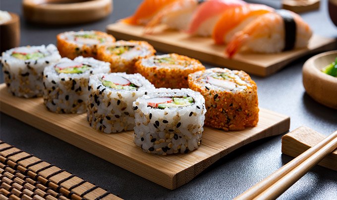 Assorted sushi rolls and nigiri served on wooden platters | MSC Cruises