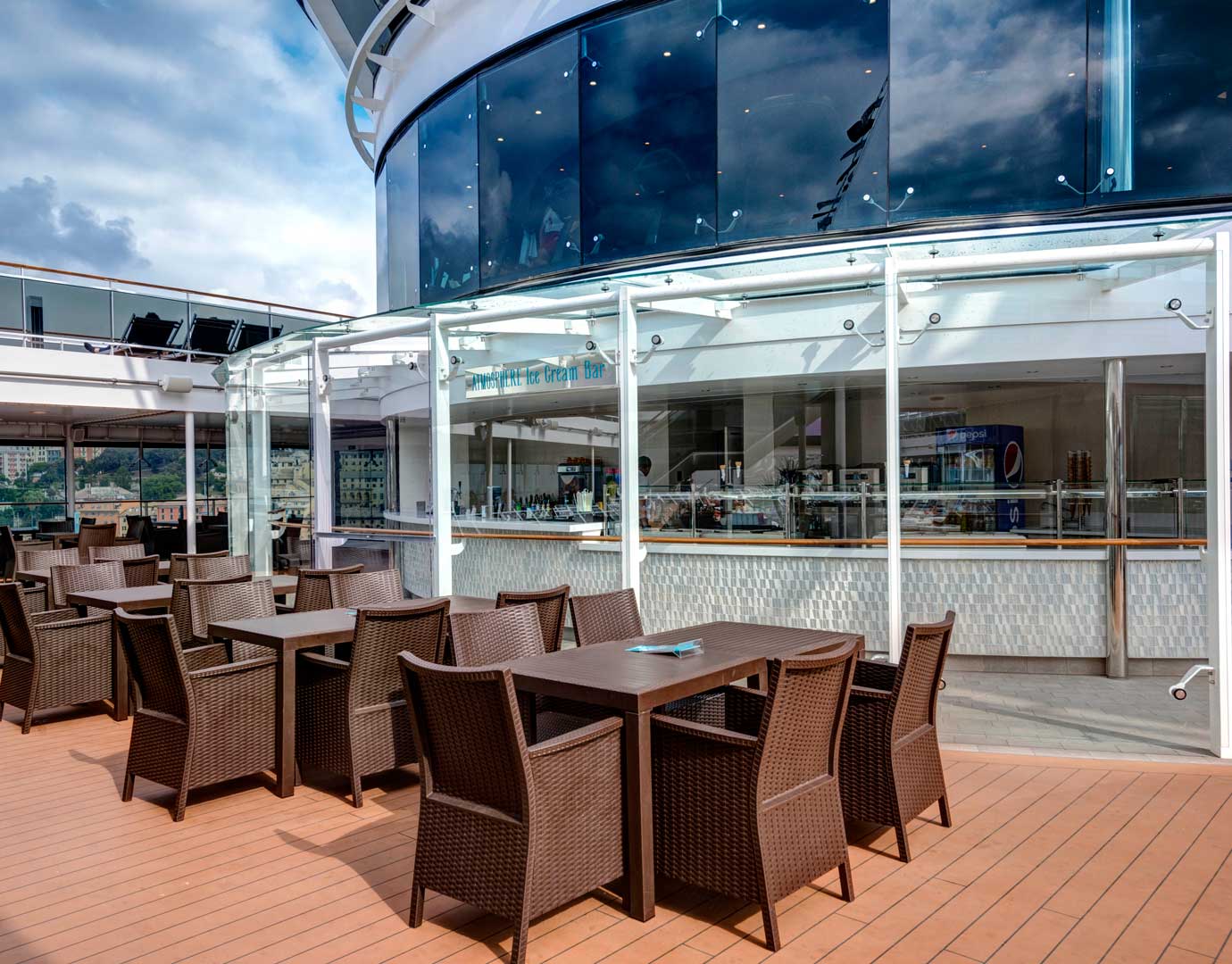 Outdoor seating area with wicker chairs and tables near an ice cream bar on an MSC cruise ship | MSC Cruises Outdoor seating area with wicker chairs and tables near an ice cream bar on an MSC cruise ship | MSC Cruises