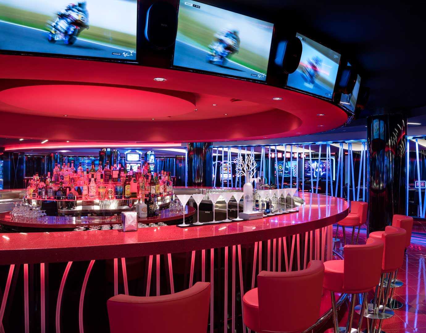 A vibrant cruise ship bar with red seating and illuminated liquor display | MSC Cruises A vibrant cruise ship bar with red seating and illuminated liquor display | MSC Cruises