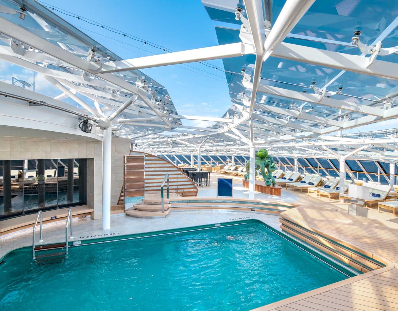 A modern cruise ship pool deck with sun loungers and a glass canopy | MSC Cruises A modern cruise ship pool deck with sun loungers and a glass canopy | MSC Cruises