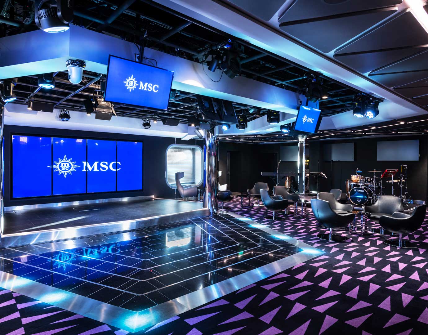 A modern entertainment lounge with stage, instruments, and MSC branding | MSC Cruises A modern entertainment lounge with stage, instruments, and MSC branding | MSC Cruises