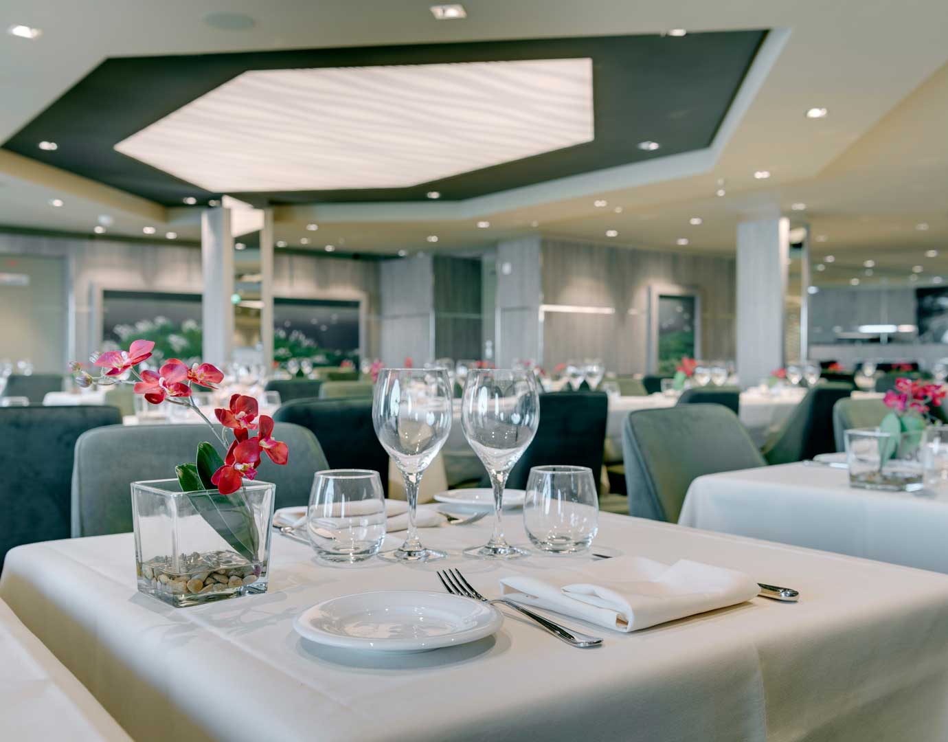 Elegant dining room with neatly set tables and floral centerpieces on an MSC cruise ship | MSC Cruises Elegant dining room with neatly set tables and floral centerpieces on an MSC cruise ship | MSC Cruises