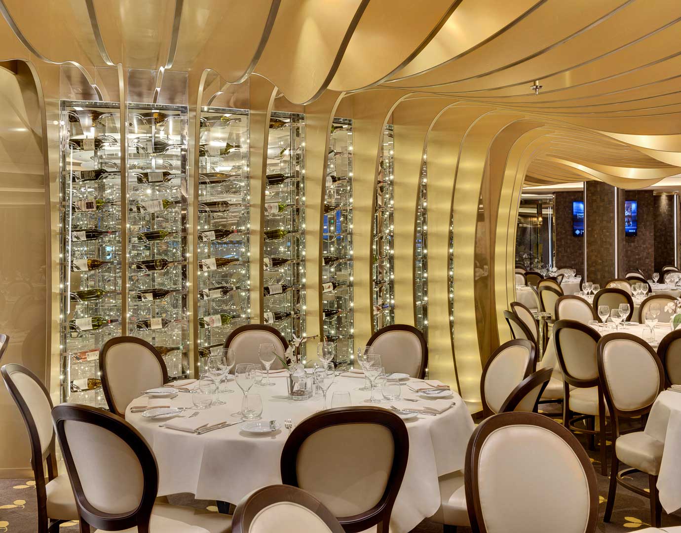 Elegant cruise ship dining room with golden decor and wine display | MSC Cruises Elegant cruise ship dining room with golden decor and wine display | MSC Cruises
