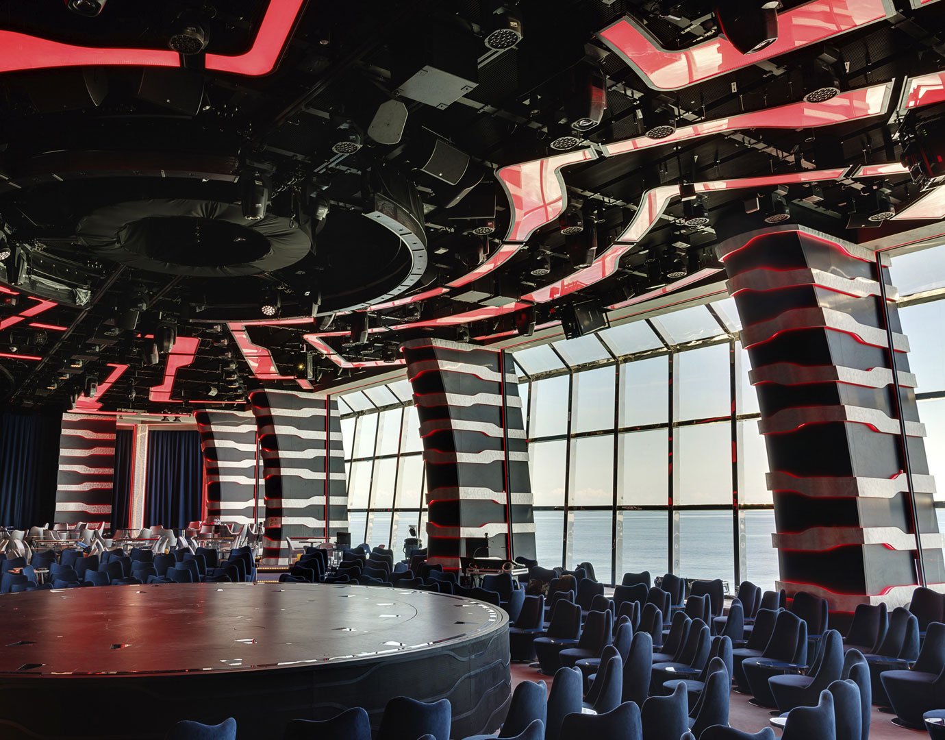 Modern theater with curved red-accented walls and ocean views onboard a cruise ship | MSC Cruises Modern theater with curved red-accented walls and ocean views onboard a cruise ship | MSC Cruises