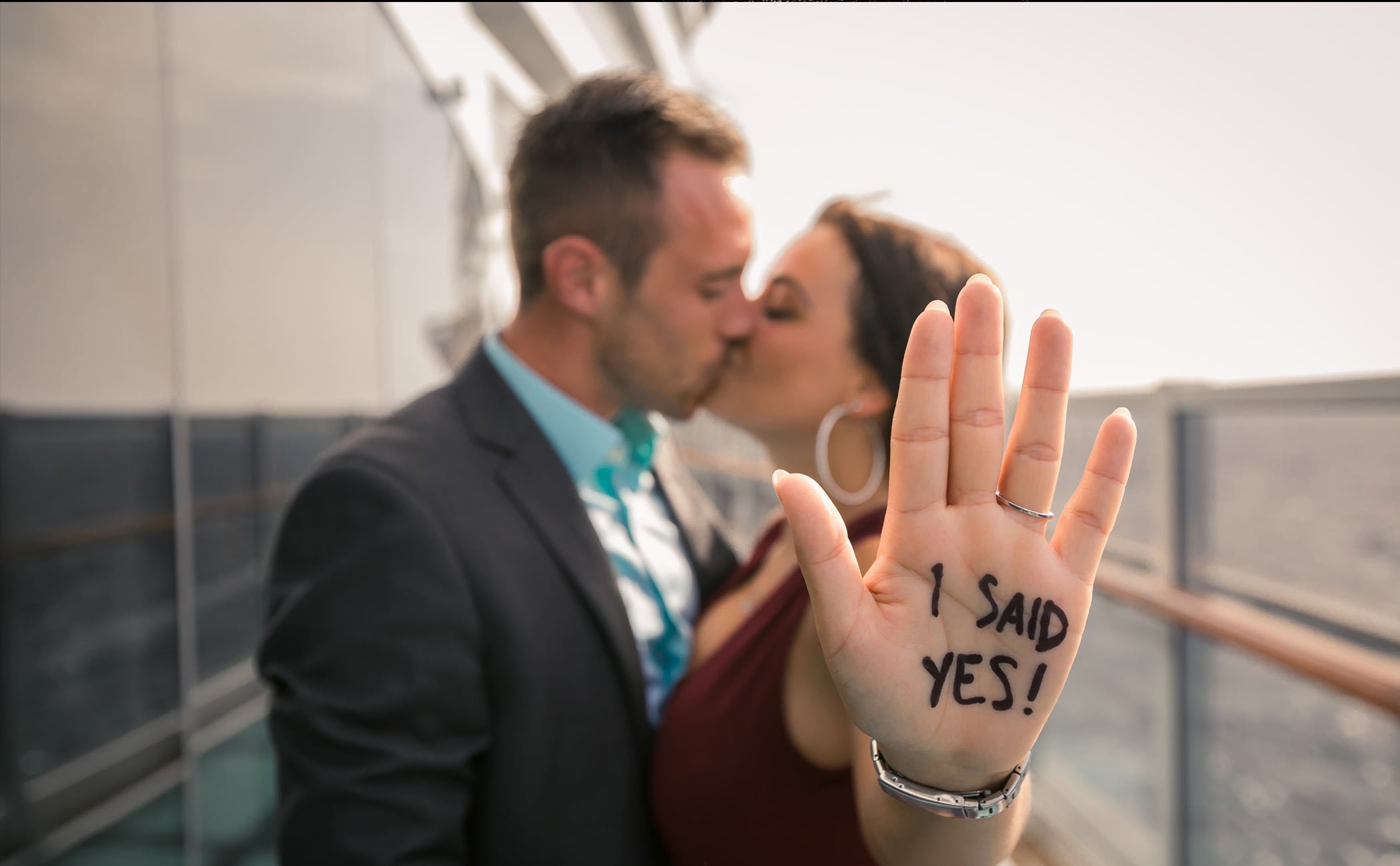A couple celebrating an engagement on a cruise ship deck with 'I said yes!' written on her hand | MSC Cruises