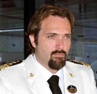 A cruise ship captain in a white uniform with gold accents onboard a ship | MSC Cruises A cruise ship captain in a white uniform with gold accents onboard a ship | MSC Cruises